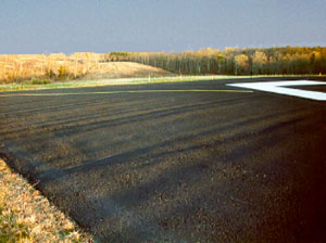 Overview photo of the end of a runway pavement.  Within the photo a series of deep transverse corrugations are visible on the pavement.