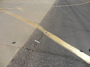 Overview photo showing a longitudinal joint between a PCC and an asphalt pavement.            The photo shows a slight amount of shoving of the asphalt for a short distance along the joint.