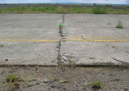 Overview photo of a transverse PCC joint with a low-severity blowup.  A slight difference in height is noticeable between the two slabs.