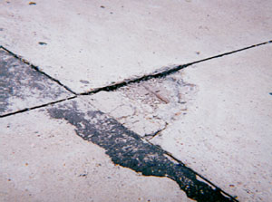 Close-up of a high-severity corner spall.  The corner spall is highly deteriorated and shows signs of loose material.