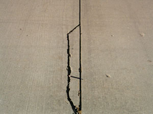 Close-up photo of a low-severity joint spall.  The spall is a fairly long but narrow spall, and is defined by a single medium-severity crack.