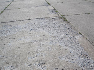 Overview photo showing showing high-severity scaling.  The PCC pavement surface in this photo           is severely scaled, and there is noticeable loose material on the surface.